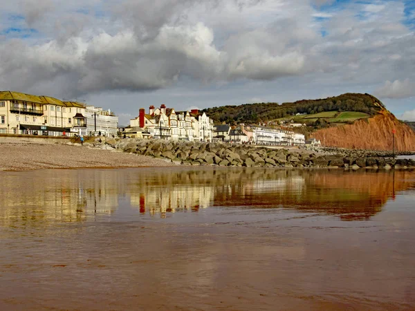 View of the eastern end of Sidmouth Esplanade and sandstone cliff. This cliff has regular rockfalls which reduce the lengths of the gardens on top. Stock Photo