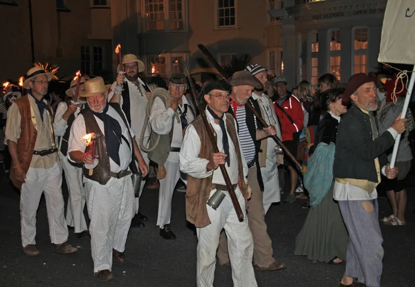 Sidmouth, Devon, England-10 augusti 2012: en grupp män klädda som pirater ta del i nattetid stängning procession av folk vecka. — Stockfoto