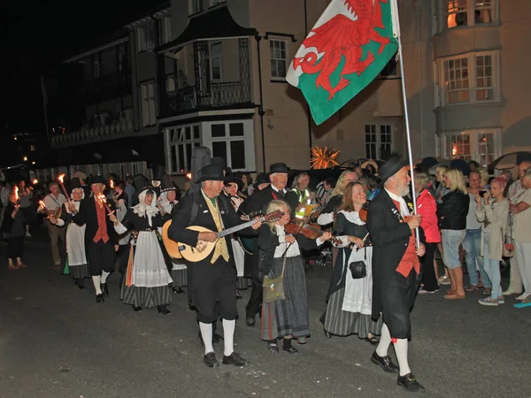 Sidmouth, Devon, England-10 augusti 2012: en grupp walesiska artister tar del i nattetid stängning procession av folk vecka. — Stockfoto