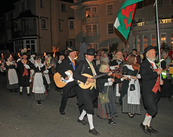 Sidmouth, Devon, England-10 augusti 2012: en grupp walesiska artister tar del i nattetid stängning procession av folk vecka. — Stockfoto