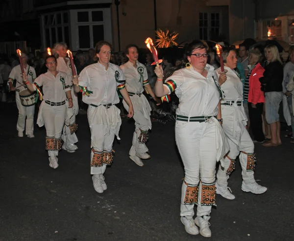 Sidmouth, Devon, England-10 augusti 2012: en trupp av Young Lady Morris dansare hålla sina flammande facklor som de deltar i nattetid stängning procession av folk vecka — Stockfoto