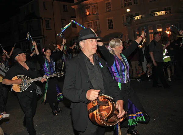 Sidmouth, Devon, England-10 augusti 2012: en grupp av musiker och täppa dansare klädda i mauve och grön delta i natten stängning procession av folk vecka — Stockfoto