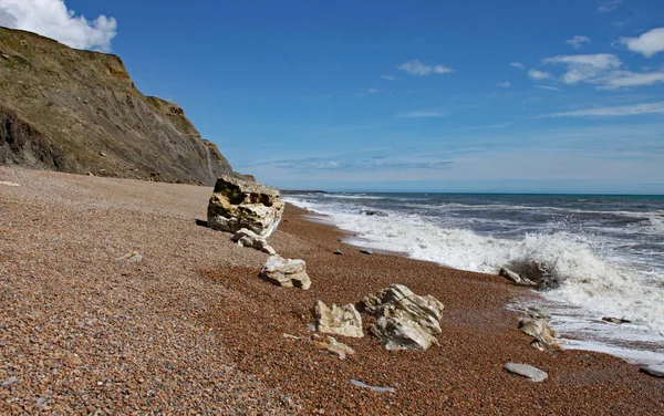 Den klapperstensstrand vid Eype i Dorset en solig dag, sandstensklippor på Jurassic Coast kan ses i bakgrunden — Stockfoto