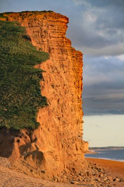 Dorset, İngiltere'deki West Bay'deki kumtaşı kayalıklar. Bu, Devon'daki Exmouth'tan Dorset'teki Studland Körfezi'ne kadar uzanan Jurassic sahilinin bir parçasıdır.
