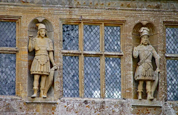 Zwei Geschnitzte Figuren Stehen Auf Beiden Seiten Von Bleiverglasten Fenstern — Stockfoto