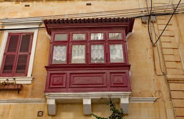 SLIEMA, MALTA - 31 Ekim 2019: Aşağıdan görülen geleneksel bir Malta körfezi penceresi elektrik kablolarının yanında duruyor.