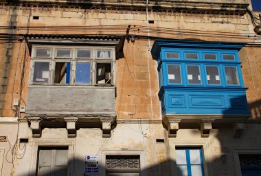 Malta, Sliema 'da iki pencere var. Bir pencere temiz ve boyanmış, diğeri tadilat aşamasında.