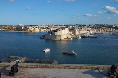 UPPER BARRAKKA GARDENS, VALLETTA, MALTA - 10 Kasım 2019: Selamlama Bataryası topları limanın karşısındaki Fort St Angelo 'yu işaret ediyor.