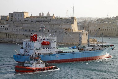 VALLETTA, MALTA - 16 Kasım 2019: bir kargo gemisine Valletta limanına bir pilot gemi eşlik ediyor
