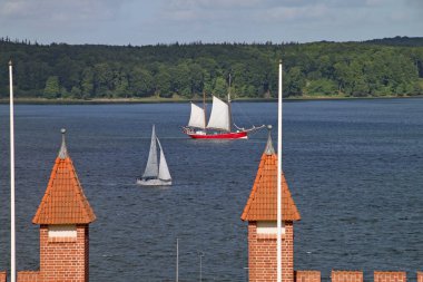 Almanya 'nın kuzeyinde Schleswig Holstein eyâletinde, Flensburg Fjord boyunca kırmızı gövdeli bir yelkenli gemi yelken açıyor.