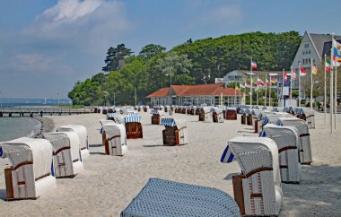 Almanya 'nın kuzeyinde Schleswig-Holstein eyâletinde sessiz bir plajda kapüşonlu kırılan tipik sandalyeler.