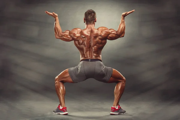 Hombres musculares fuertes flexionando los músculos de la espalda. Está mostrando el desarrollo de los músculos de la espalda —  Fotos de Stock
