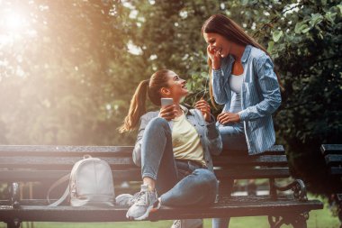 İki Kadın Arkadaş Parkta Telefonda Müzik Dinleme keyfini çıkarın