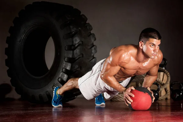 Muskularne mężczyźni robi push-up na piłkę medycyny jako część jego trening krzyżowy trening — Zdjęcie stockowe