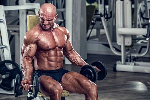 Culturista haciendo ejercicio con sombrillas en el gimnasio —  Fotos de Stock