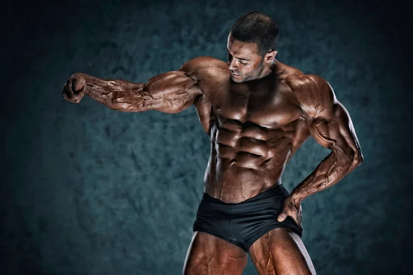 Schöner muskulöser Bodybuilder, der die Muskeln spielen lässt — Stockfoto