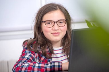 Genç kız onun ödev dizüstü bilgisayar ile gülümseyen