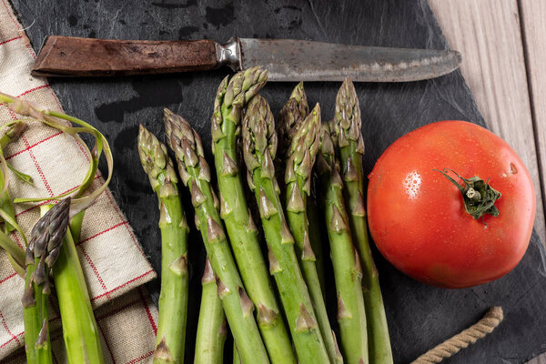 bunch of fresh asparagus with tomato on a slate plate