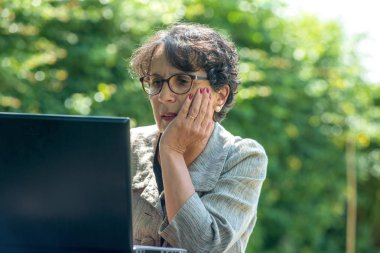 Bahçede dizüstü bilgisayar kullanan olgun bir esmer.
