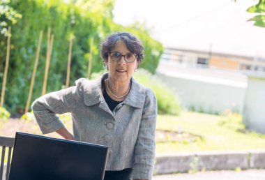 Bahçede dizüstü bilgisayar kullanan olgun bir esmer.