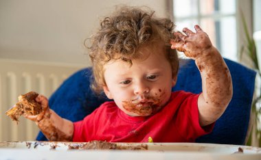 bir bebek bir çikolatalı kek yiyor