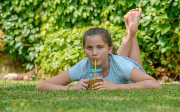 Sorrindo Adolescente Menina Deitada Grama Beber Suco Laranja — Fotografia de Stock