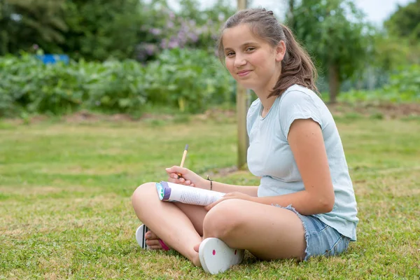 Een Jonge Tiener Met Gekruiste Benen Zitten Schrijven Het Gras — Stockfoto