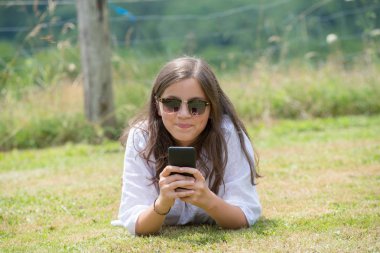 güzel bir genç kız güneş gözlüğü ile smartphone kullanarak