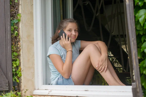 Egy Fiatal Tizenéves Lány Ablak Mellett Használ Egy Smartphone — Stock Fotó