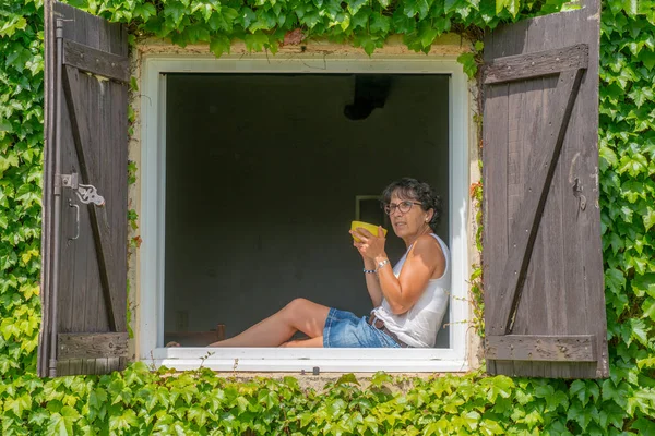 ウィンドウで座っていると お茶を飲む女性 — ストック写真