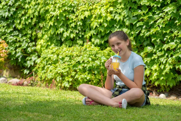 Ung Tonåring Flicka Sitter Gräset Och Dricka Apelsinjuice — Stockfoto