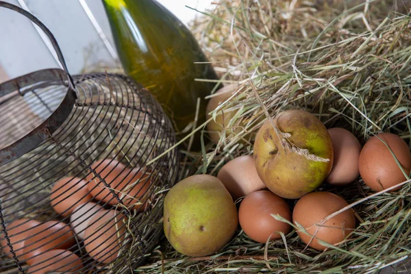 eggs, apples and a bottle of cider on the straw