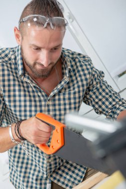 bir el testeresi kullanan bir genç adam