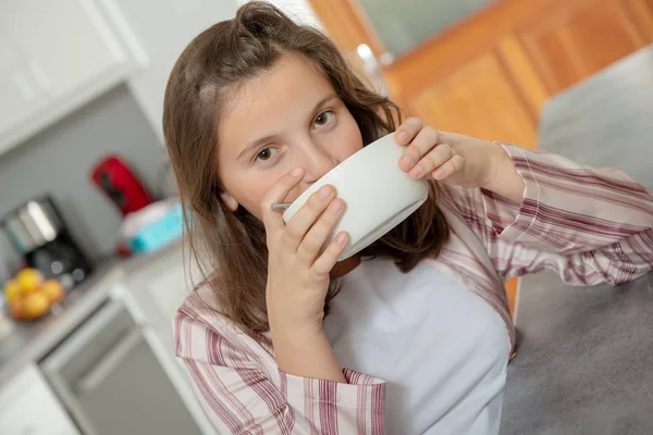 一个十几岁的女孩正在碗里喝咖啡 — 图库照片