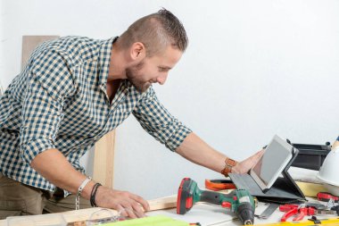 Genç bir adam evde tamircilik tablet kullanma