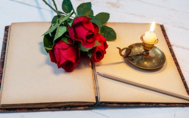 Eski defter, güller ve küçük mum, romantik bir kavram.