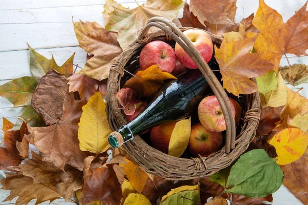 篮子里有一瓶苹果酒和苹果的秋叶 — 图库照片