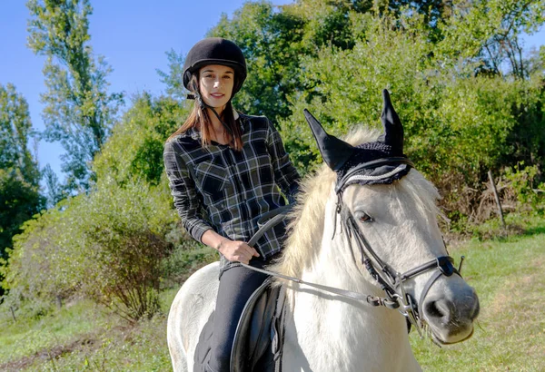 骑着白马的带着黑色头盔的年轻女子 — 图库照片
