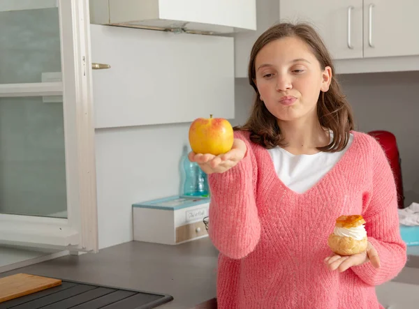 十几岁的女孩选择了一个甜糕点和有机苹果 — 图库照片