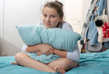 dalgın genç kız oturan yastık ile çapraz-yatakta bacaklar