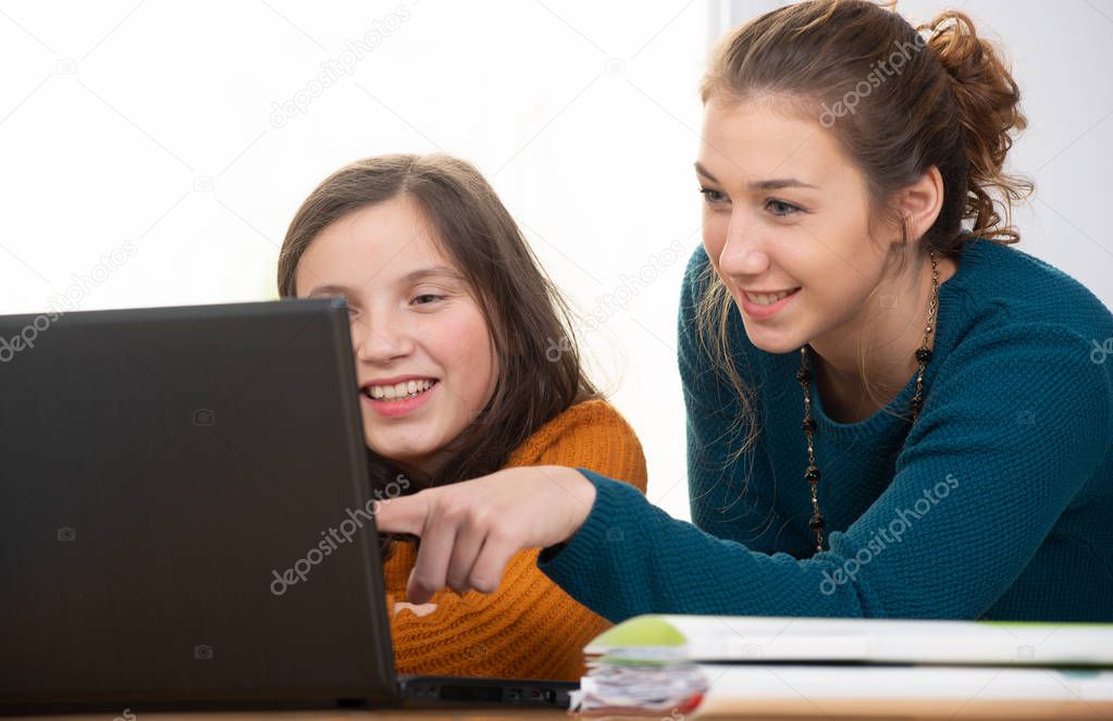 young woman helps a teen girl with  homework