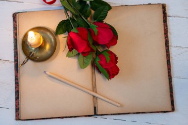 Eski defter, güller ve küçük mum, romantik bir kavram.