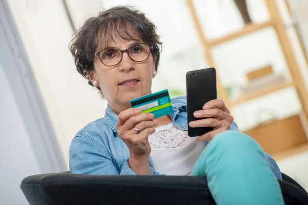 Eine ältere brünette Frau, die mit dem Internet einkauft — Stockbild Eine Ältere Brünette Frau Die Mit Dem Internet Einkauft — Stockfoto