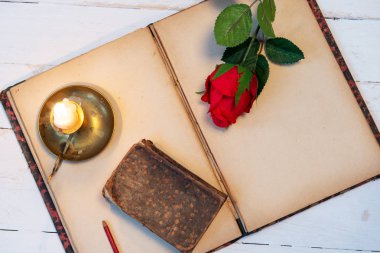 Eski defter, güller ve küçük mum, romantik bir kavram.