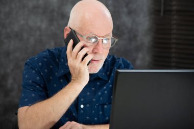 Ofiste sakallı ve mavi gömlekli olgun bir adam var.