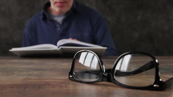 Man Läser Bok Och Med Glasögon Defocus Koncept — Stockvideo