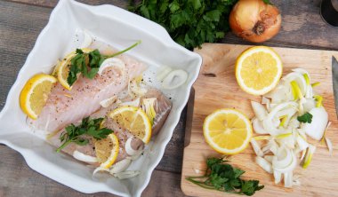 Taze balık, otlar ve limon eklenmesi ile ham morina fileto