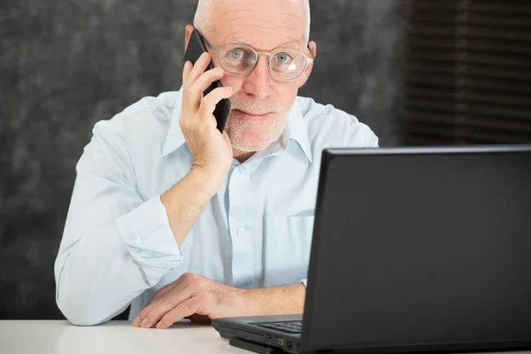 Rijpe zakenman met baard praten met telefoon op kantoor — Stockfoto