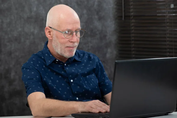 Senior avec barbe et chemise bleue dans le bureau à l'aide d'un ordinateur portable — Photo