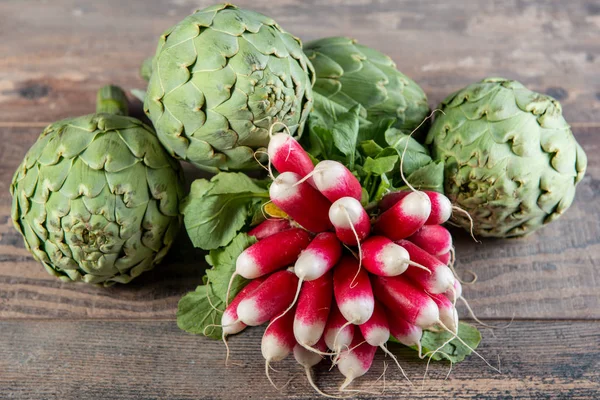 Artichokes and radishes on the wooden table — Stock Photo, Image